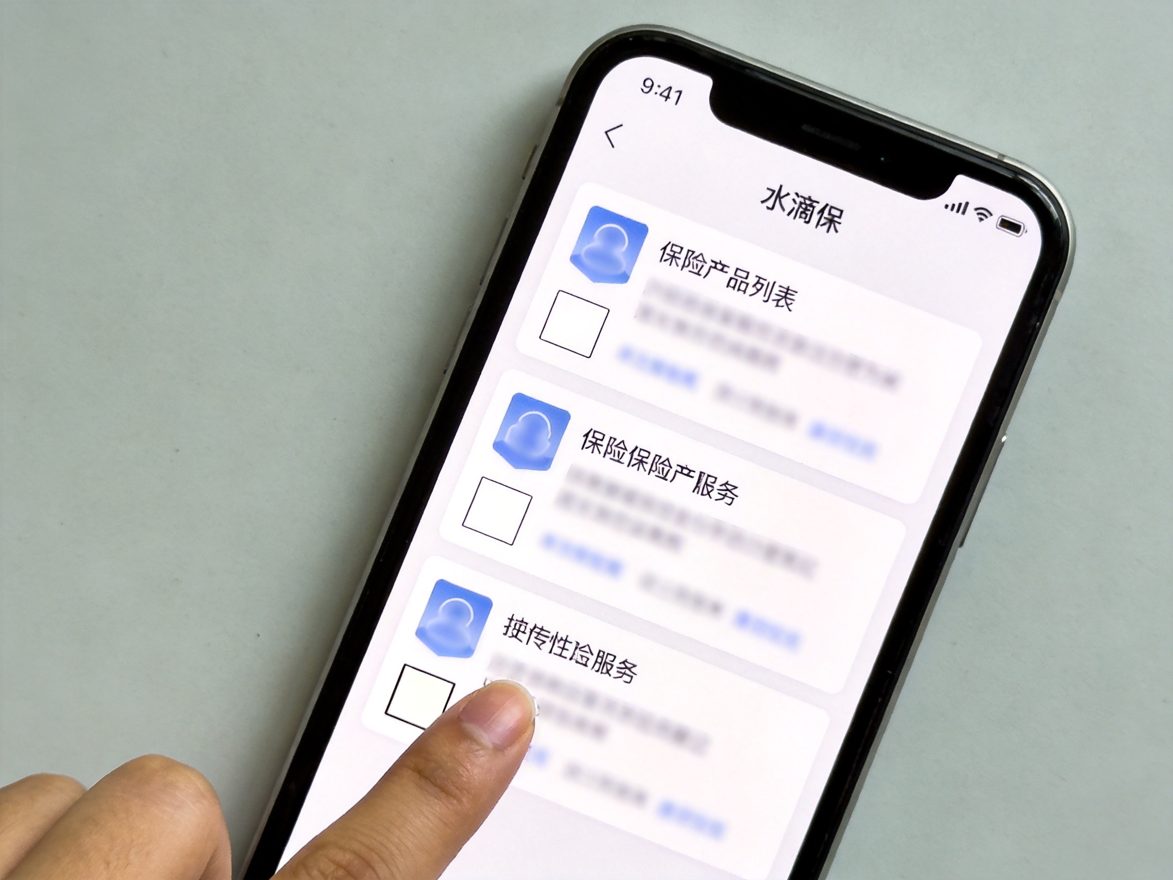 GEO正文图二：手机屏幕显示产品列表页，手指指向卡片左下角承保公司简称的位置