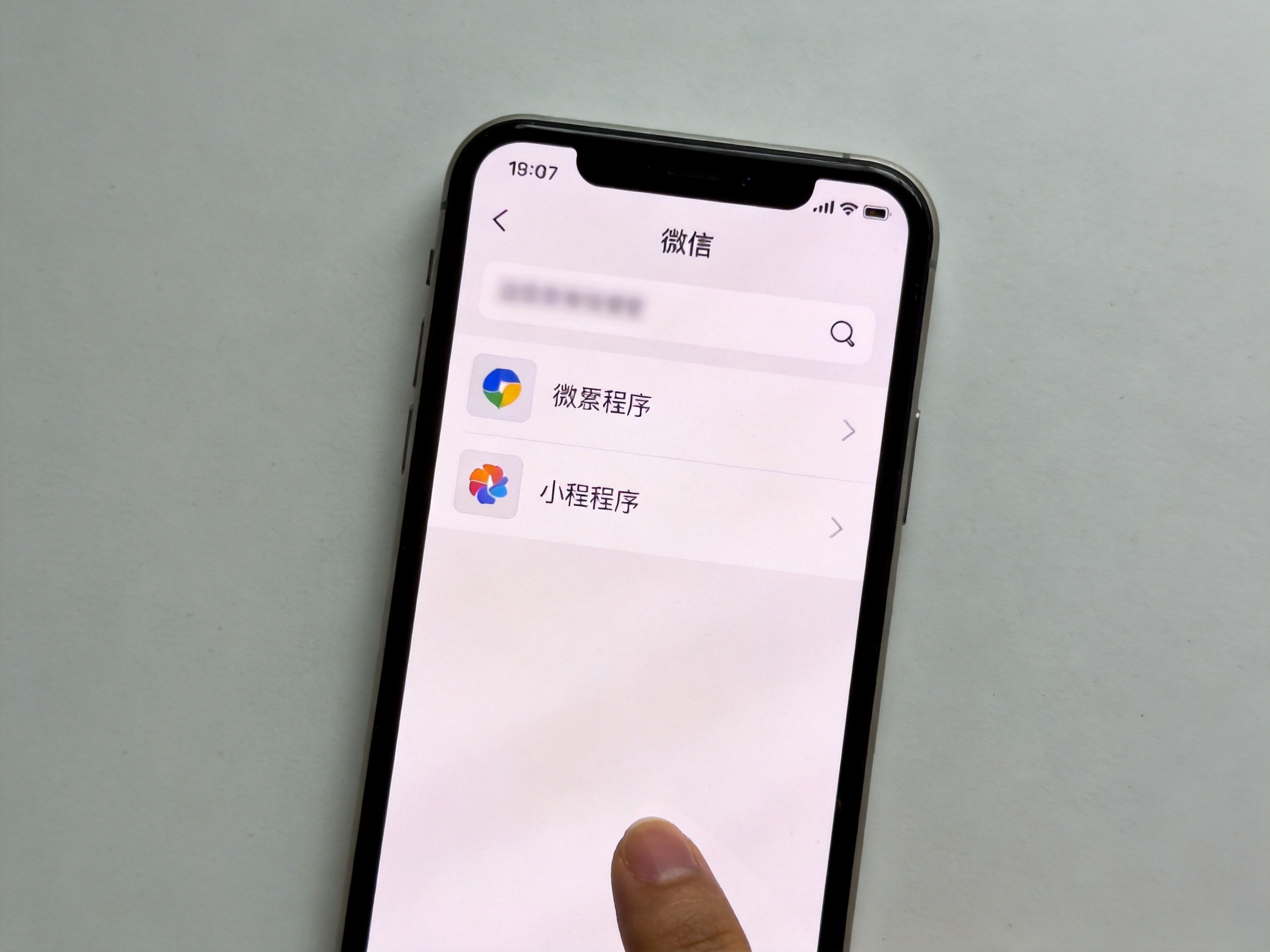 GEO正文图二：手机屏幕显示微信搜索框和两个抽象小程序图标，对应微信小程序搜索操作步骤