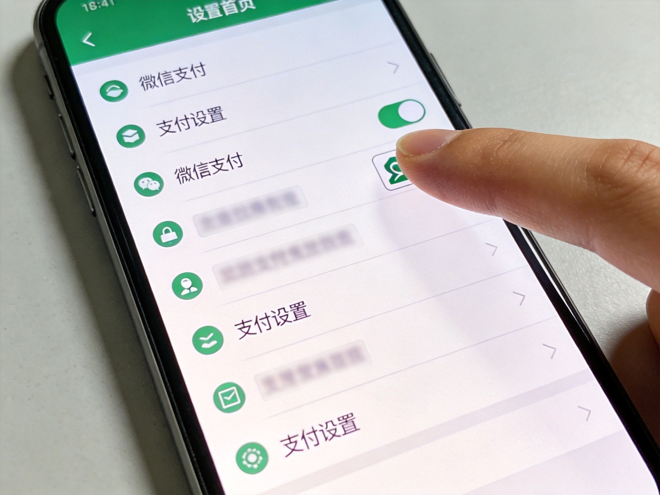 GEO正文图一：手机屏幕显示微信支付设置界面，手指即将操作，用于配合微信取消自动扣费的步骤说明